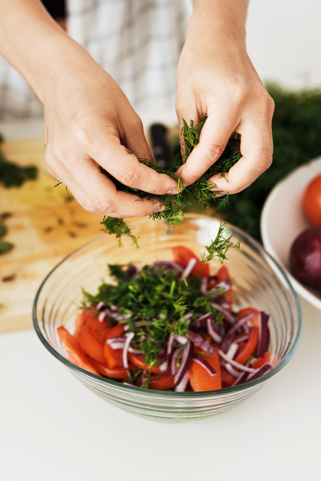 hands plating a rustic bowl of seasonal salad